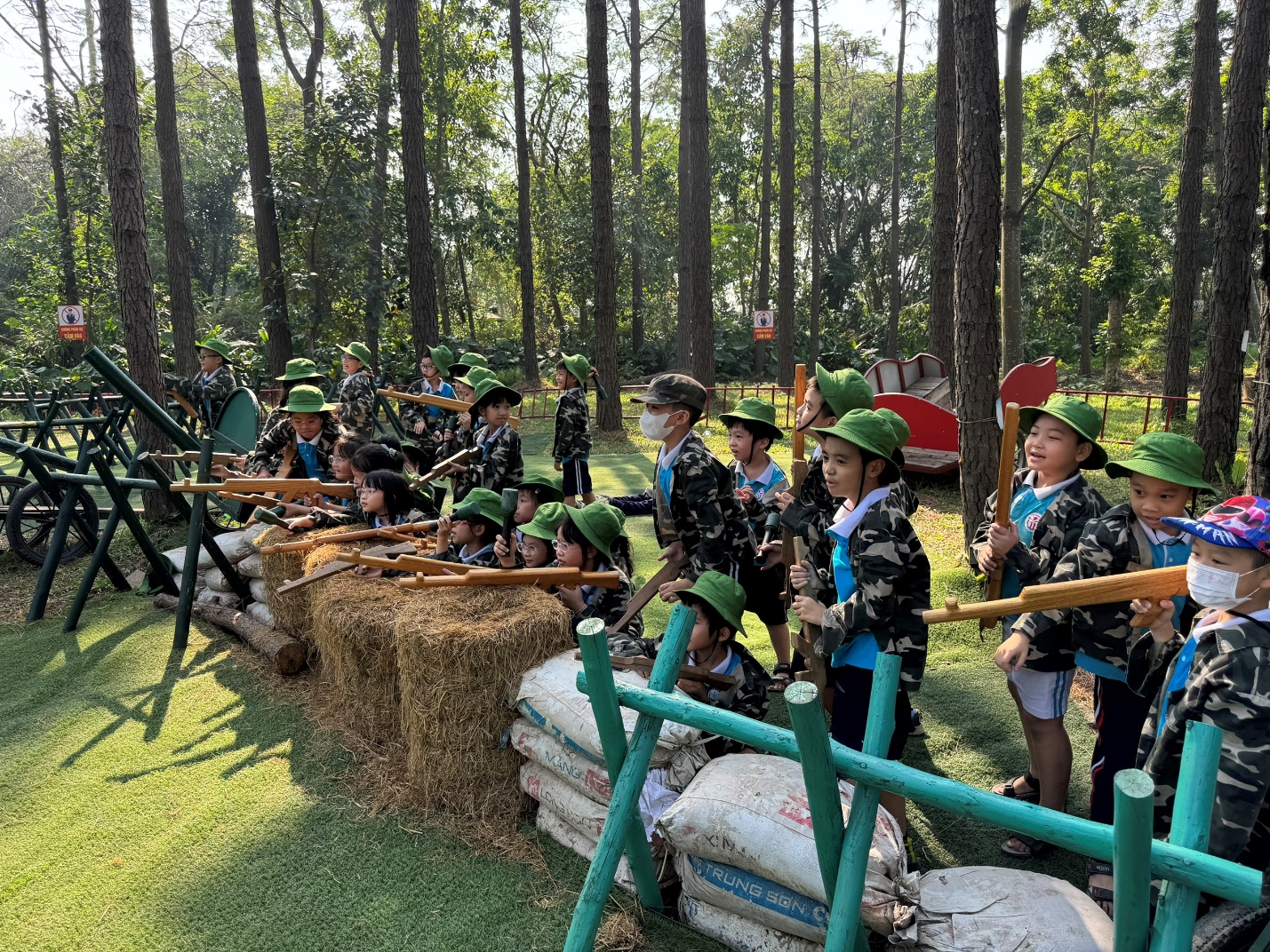 A group of kids in uniform with wooden guns

Description automatically generated
