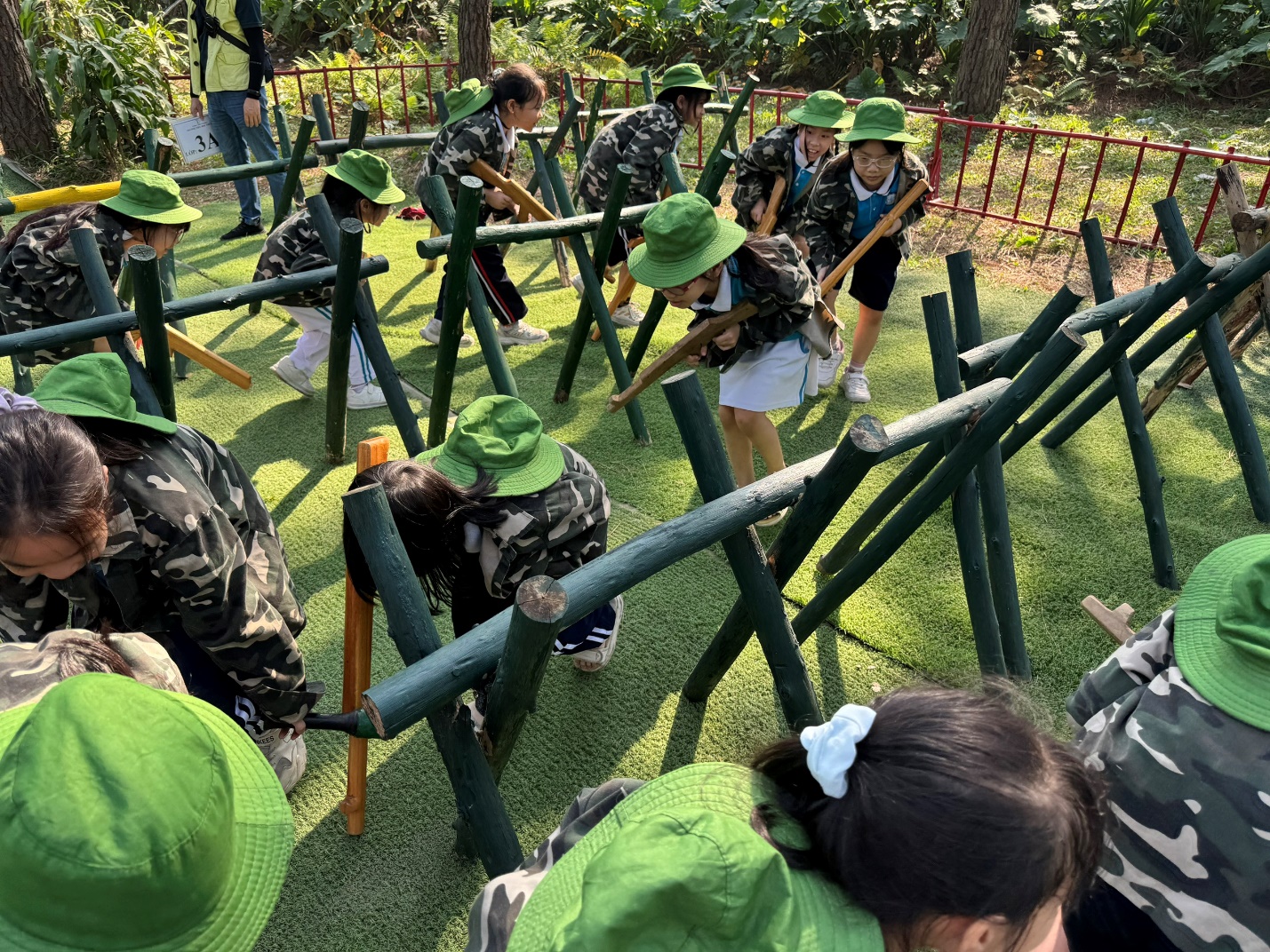 A group of people in green hats holding wooden poles

Description automatically generated
