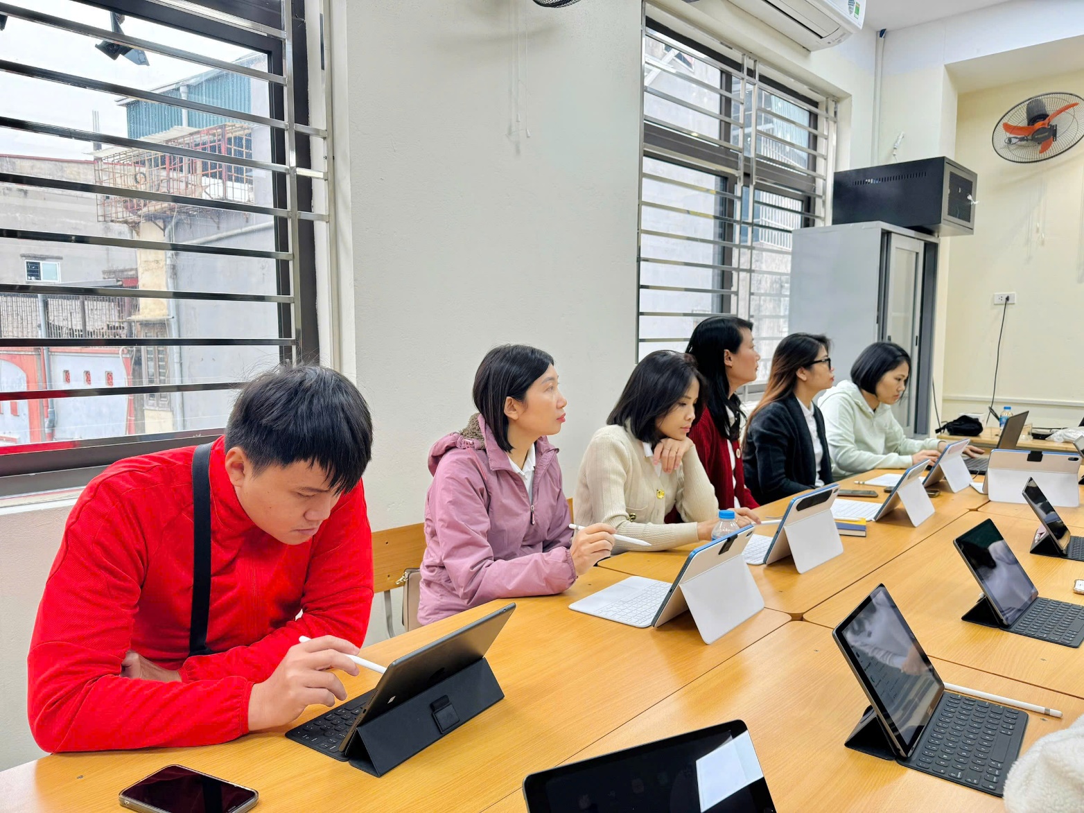 A group of people sitting at a table with laptops
Description automatically generated
