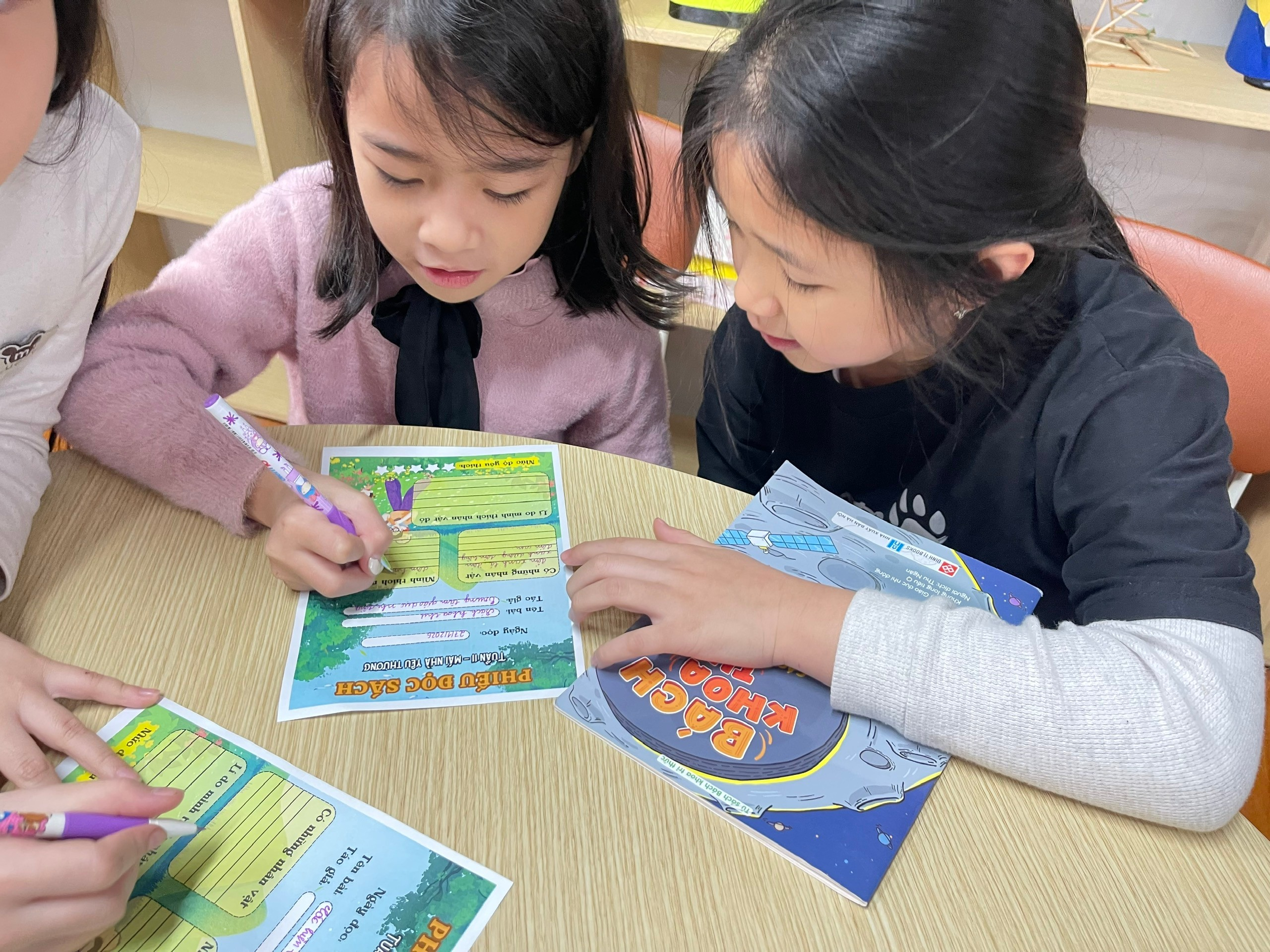 A group of children sitting at a table looking at a book

AI-generated content may be incorrect.